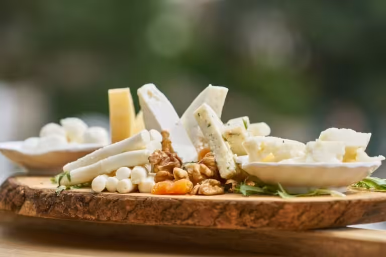 Artisan cheese board with various cheeses, walnuts, and dried apricots on a rustic wooden platter at 14 Acres.