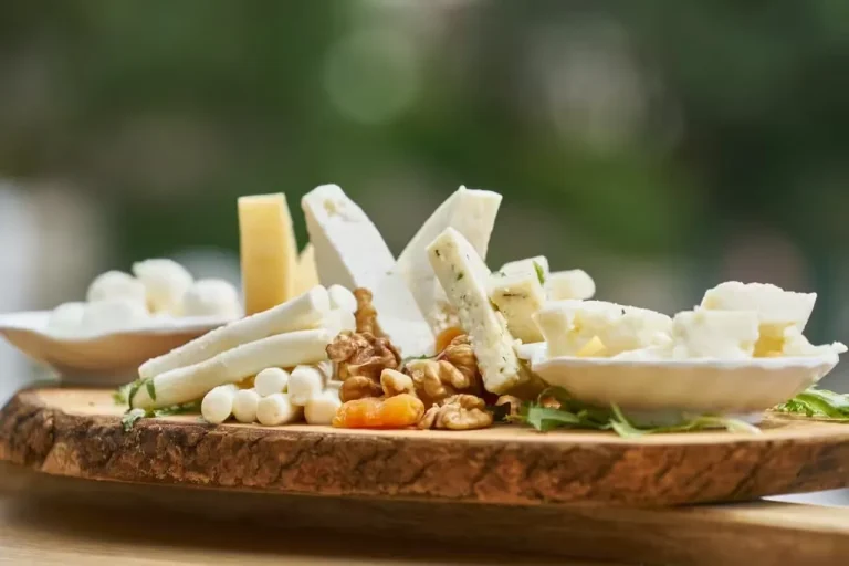 Artisan cheese board with various cheeses, walnuts, and dried apricots on a rustic wooden platter at 14 Acres.