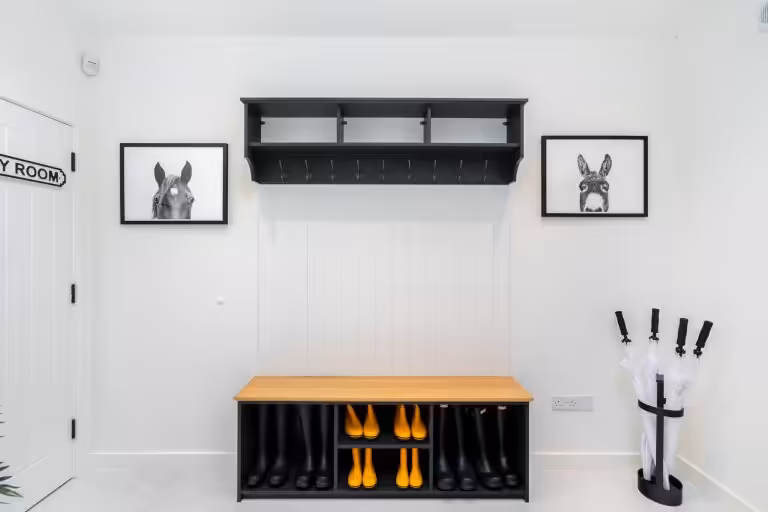 Stylish boot room interior at 14 Acres with black and yellow Hunter wellington boots, horse and donkey art, and umbrella stan