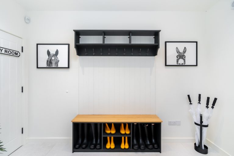 Stylish boot room interior at 14 Acres with black and yellow Hunter wellington boots, horse and donkey art, and umbrella stan
