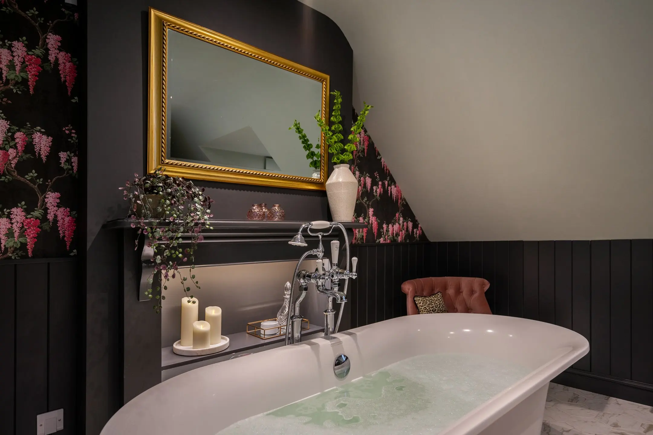 Luxury freestanding bathtub with bubbles, chrome taps, and a gold-framed mirror in a bathroom with floral wallpaper at 14 Acr