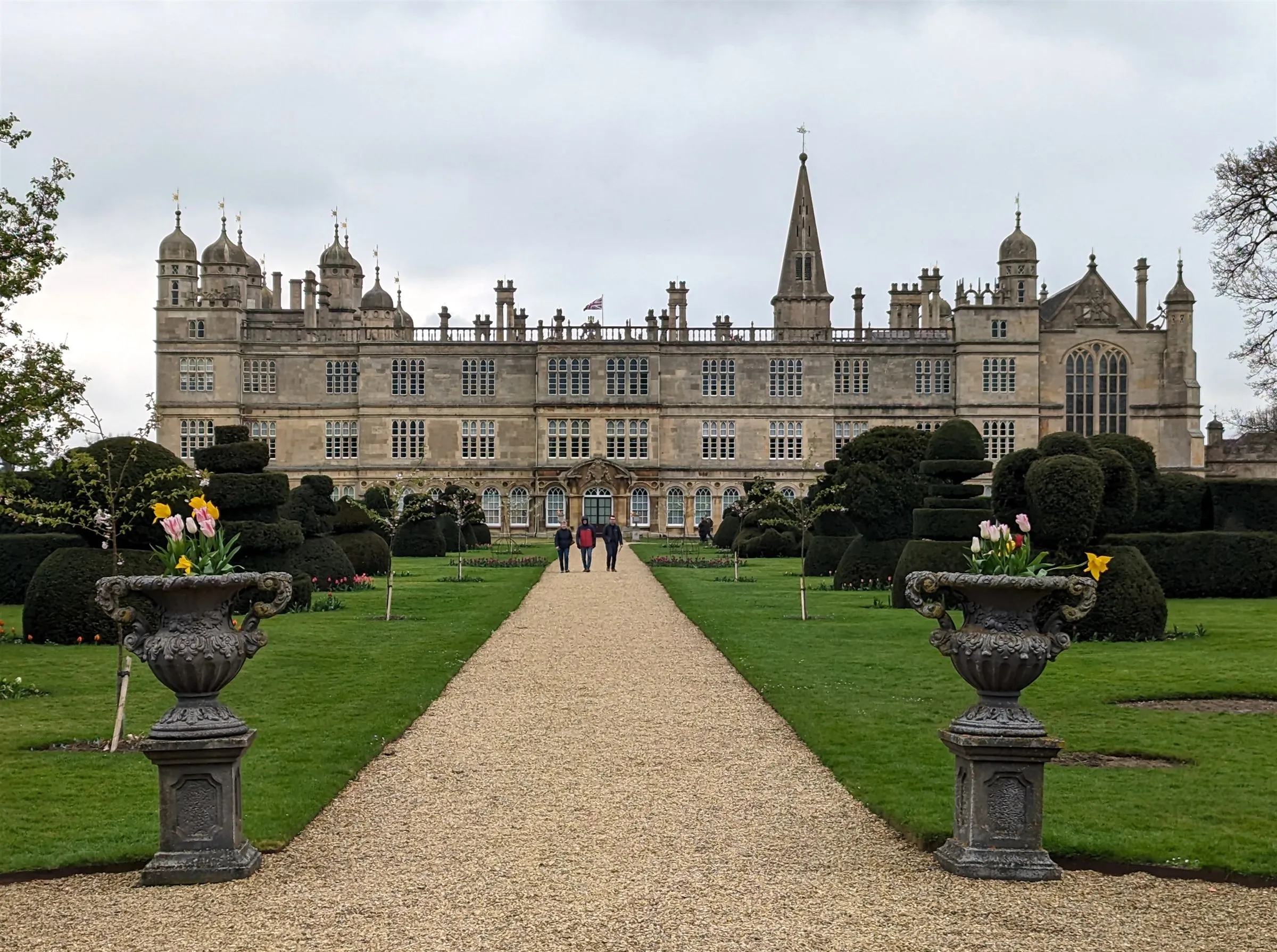 The South Garden at Burghley House with clipped topiary, stone urns and a gravel path leading to the south facade