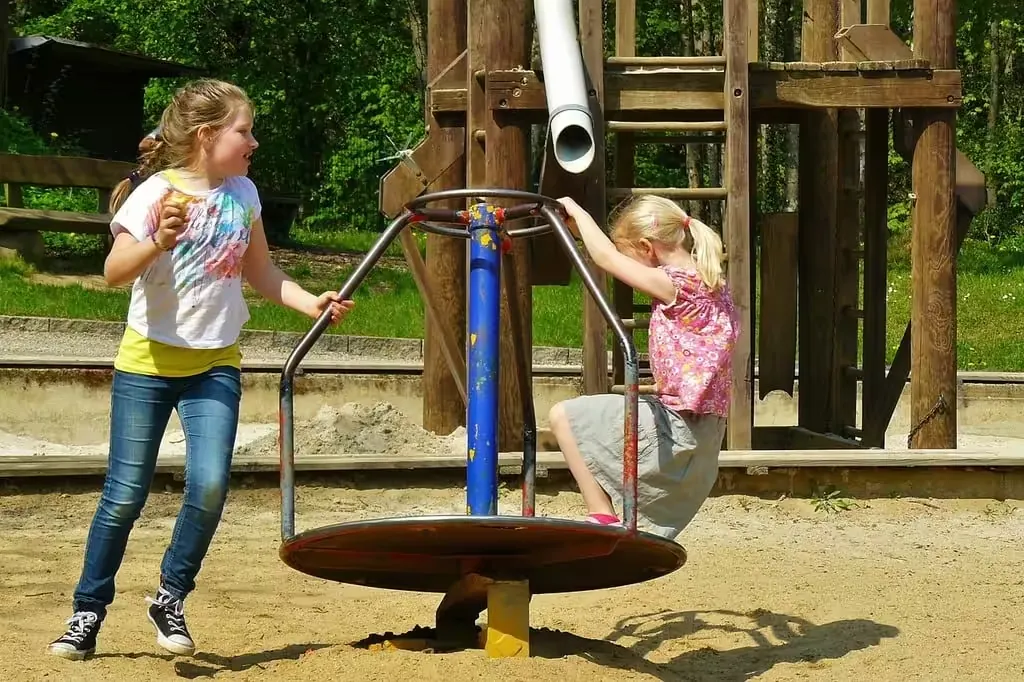 Two girls playing on a roundabout in a children's playground