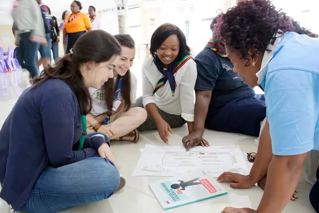 Young women in guiding uniforms working through activity sheets on the floor