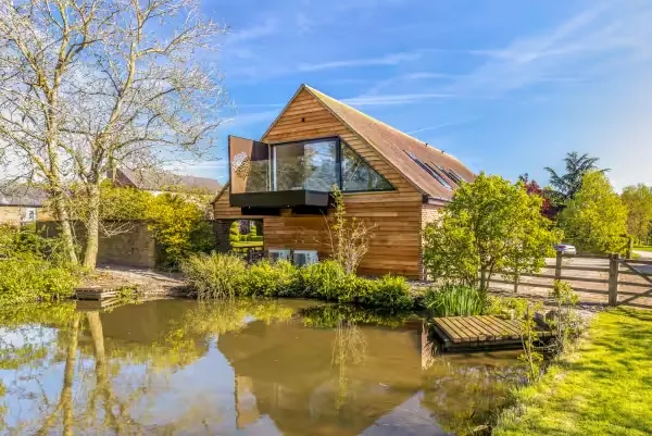The Loft at 14 Acres, a timber-clad lodge with a glass dining balcony above a private pond
