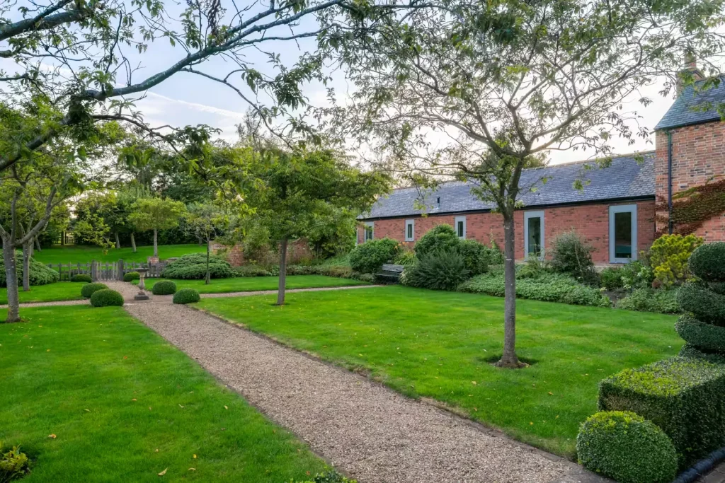 Walled garden with a gravel path, lawns, topiary and a brick barn