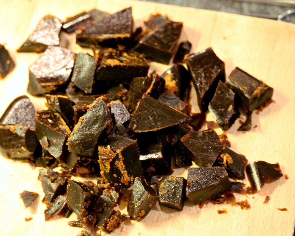 Pieces of dark homemade bonfire toffee on a wooden chopping board