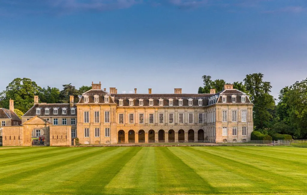 The north front of Boughton House near Kettering across a striped lawn at sunset