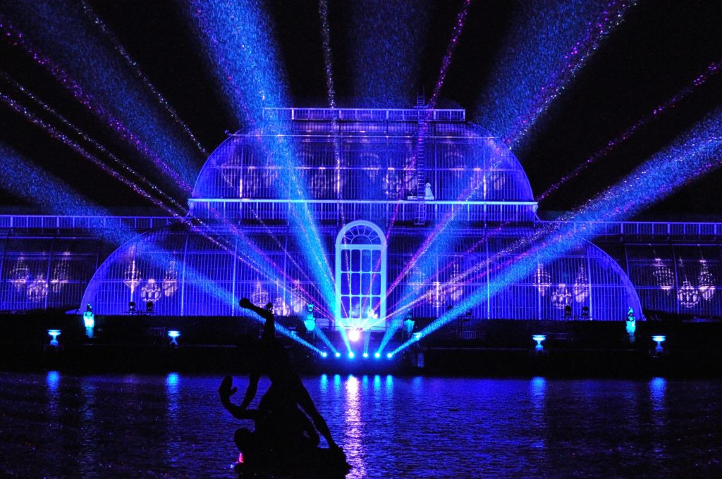 A glasshouse and garden lit with coloured illuminations on a Christmas light trail at night