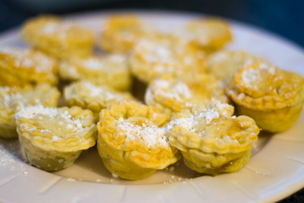 Homemade mince pies dusted with icing sugar on a white plate