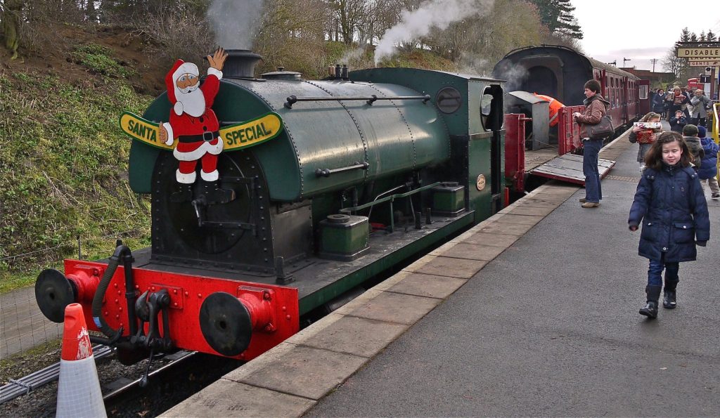A green steam locomotive decorated with a Santa Special sign at Pitsford and Brampton station on the Northampton and Lamport Railway